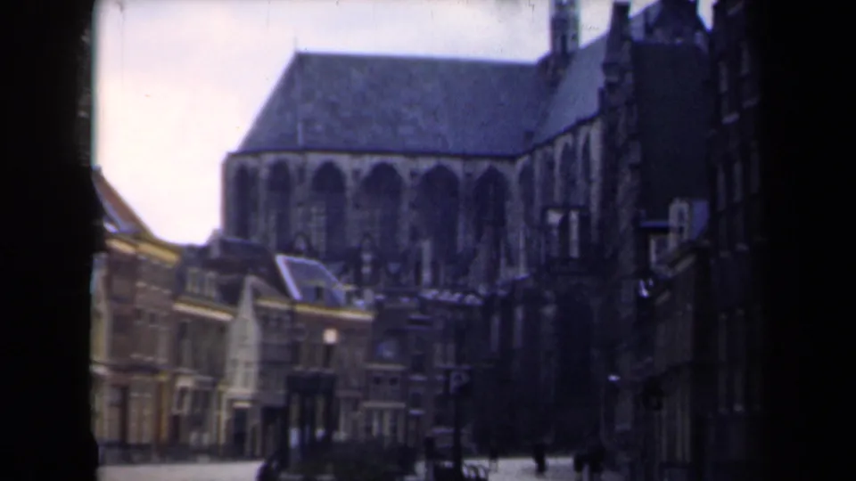 1946 Netherlands street view with a large Gothic church, traditional facades, and a few distant pedestrians under overcast light.