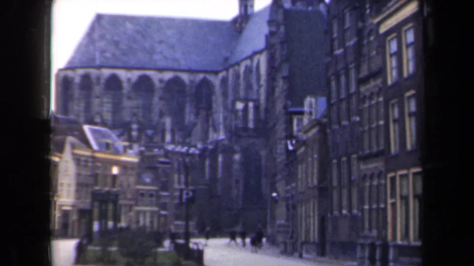 1946 Netherlands street scene with the church filling more of the frame, yellow facades at left, and pedestrians near the road.
