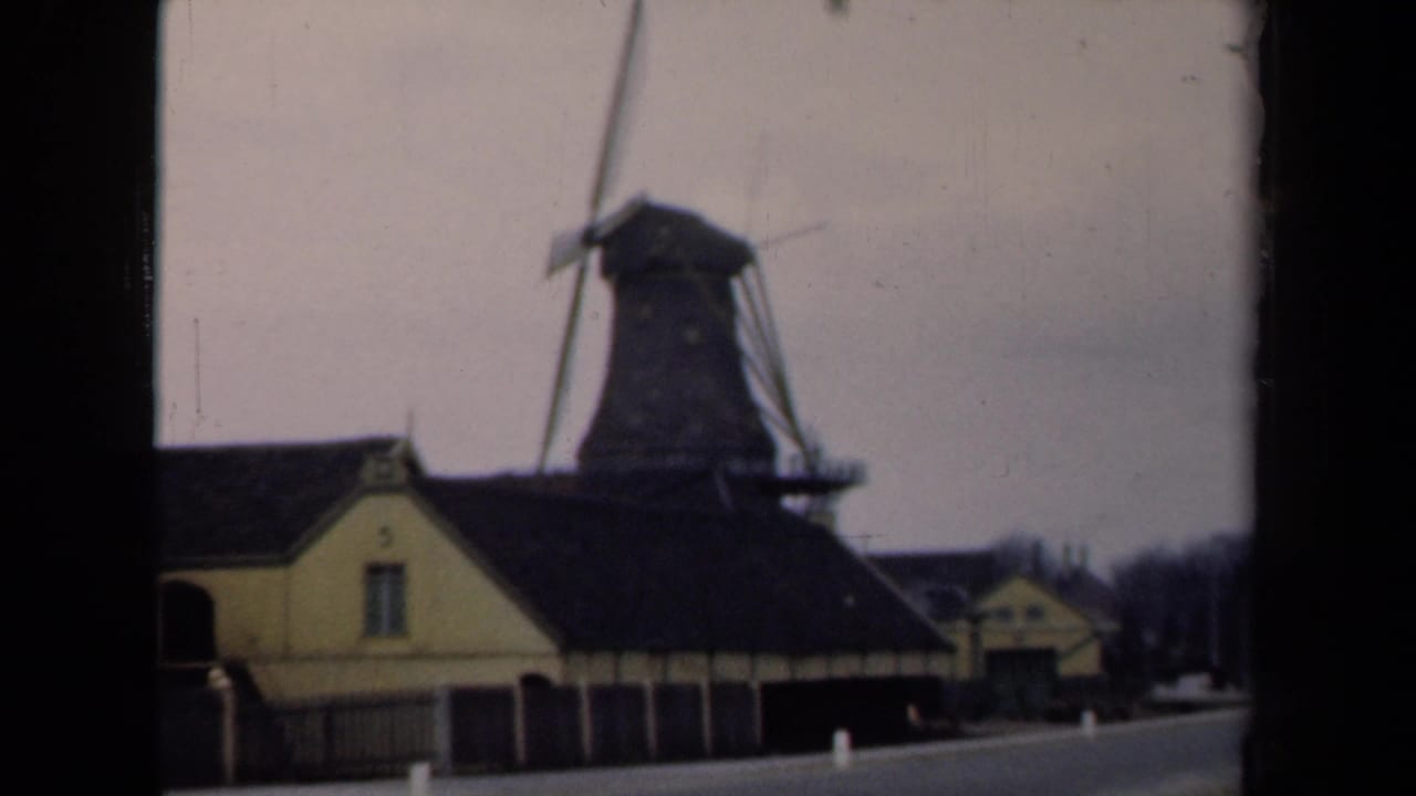 Windmill and attached yellow buildings viewed from the road with soft focus.