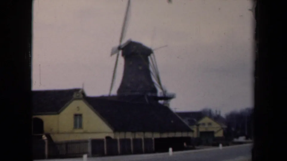 1946 Netherlands home-movie frame with a windmill complex seen from a moving road position.