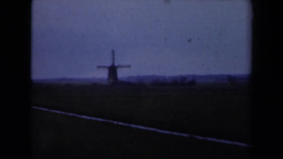 1946 Netherlands 8mm frame showing a distant windmill across flat fields in muted color.