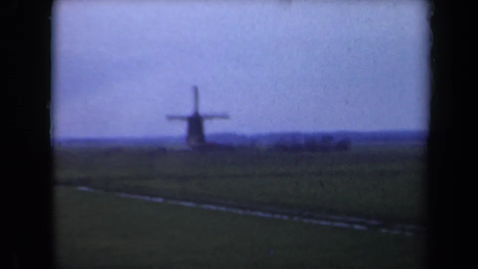 1946 Netherlands home-movie frame of a distant windmill across flat countryside under an overcast sky.