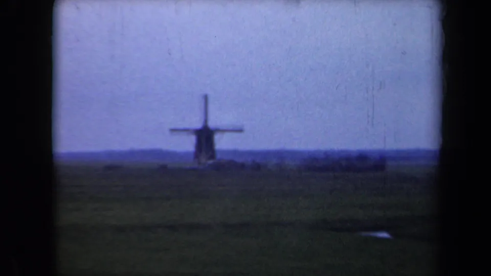Distant Dutch windmill sits near the horizon in a soft, blue-tinted 8mm home-movie frame from 1946.