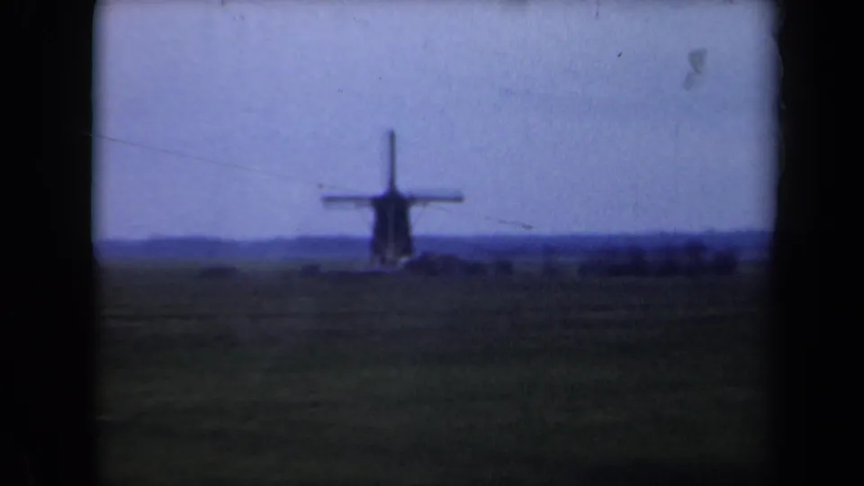 1946 Netherlands frame with a soft-focus windmill beyond open farmland, visible grain, dust marks and rounded 8mm frame edges.