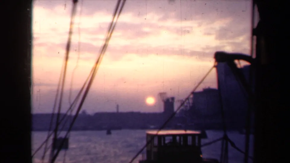 1946 Netherlands harbor sunset viewed from a boat, with rigging lines crossing the sky and shoreline in silhouette.