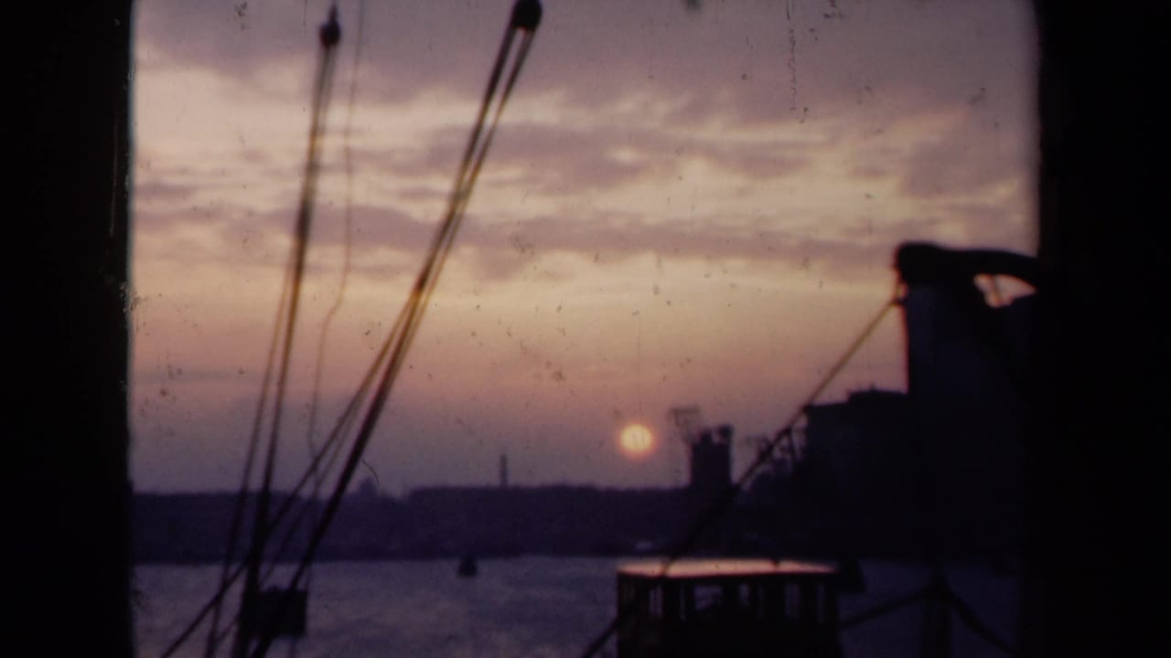 1946 Dutch harbor view at dusk, showing the sun above the waterline behind silhouetted masts, rigging, and distant industrial forms.