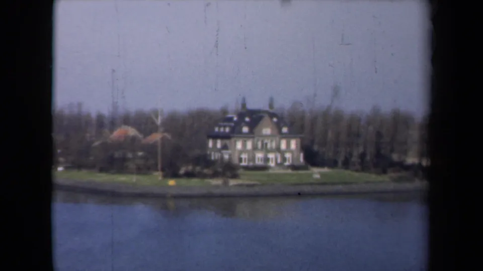 1946 Netherlands 8mm view of a large house beside water, with a lawn, bare trees, and soft home-movie color.