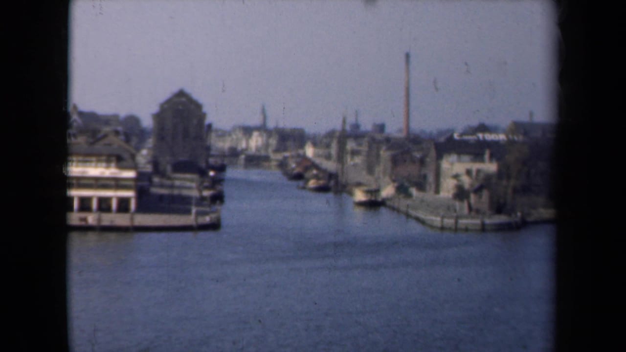 Canal scene with boats, masonry buildings, quays, and chimneys under a pale sky.