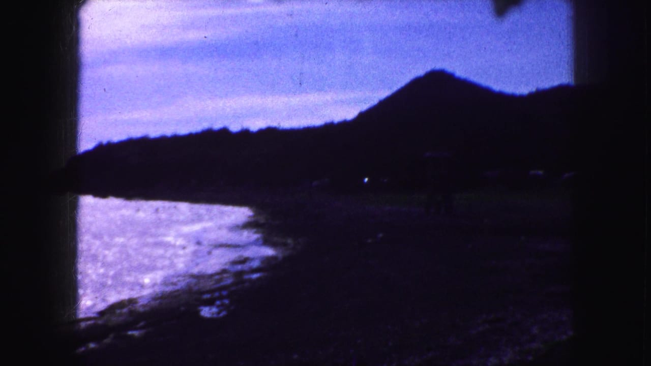 Coastal water and dark hillside framed by heavy shadow and film-edge borders.