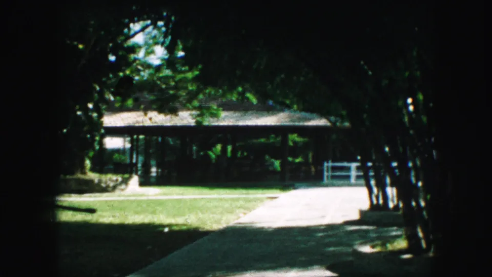 1959 Kansas City yard frame with a house exterior, broad lawn, walkway, tree shade, and a small white fence.