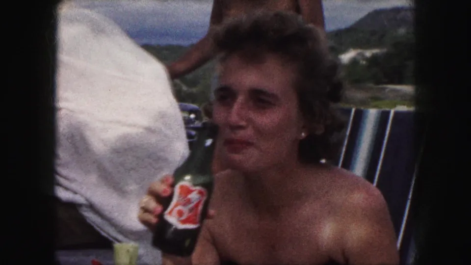 In the 1959 Kansas City-labeled clip, the seated woman turns in profile and brings the bottle closer as if about to drink.