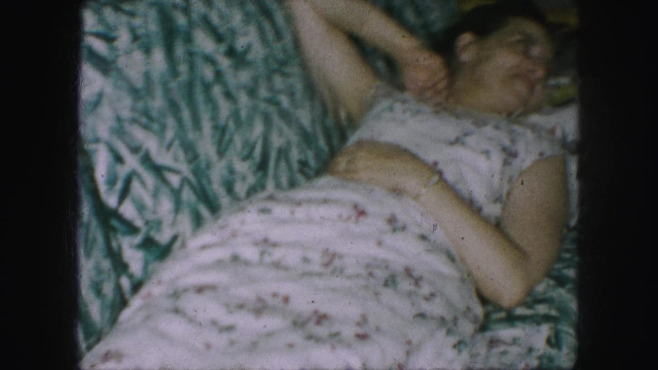 Adult woman lies on a patterned sofa with her head turned and floral dress visible.