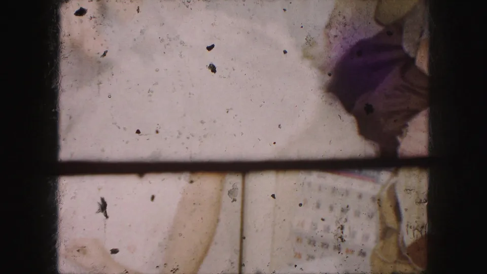 1959 Kansas City interior frame with the white dress close to camera, a partial sleeve at right, and a wall calendar behind.