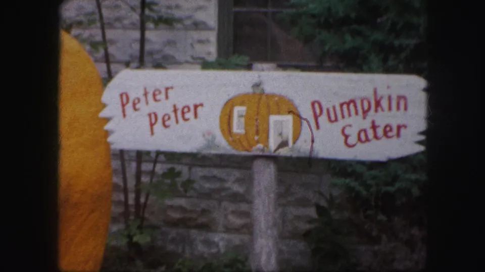 1959 Kansas City home-movie frame of the decorative Peter Peter Pumpkin Eater sign, softened by 8mm grain and handheld framing.
