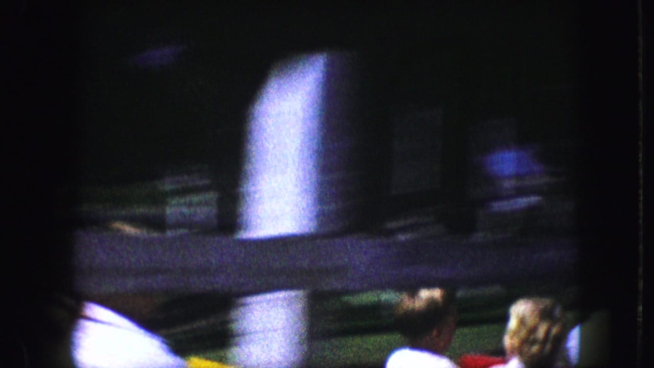 Blurred close view of coaster structure and passengers in a shaded ride area.