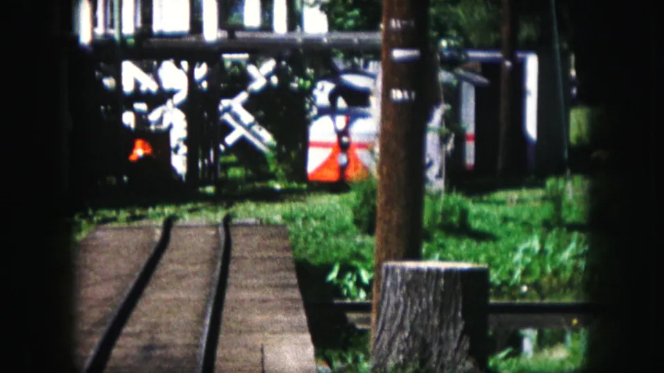 Curving miniature railway tracks, grass, posts, and small train cars appear in the Kansas City home movie.