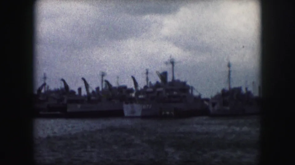 1959 home-movie frame showing a row of docked naval vessels viewed from across the water in Kansas City, Missouri.