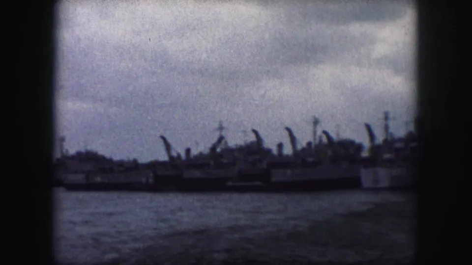 The 8mm frame holds a wide, distant view of docked naval vessels along the waterline in an overcast Missouri setting.
