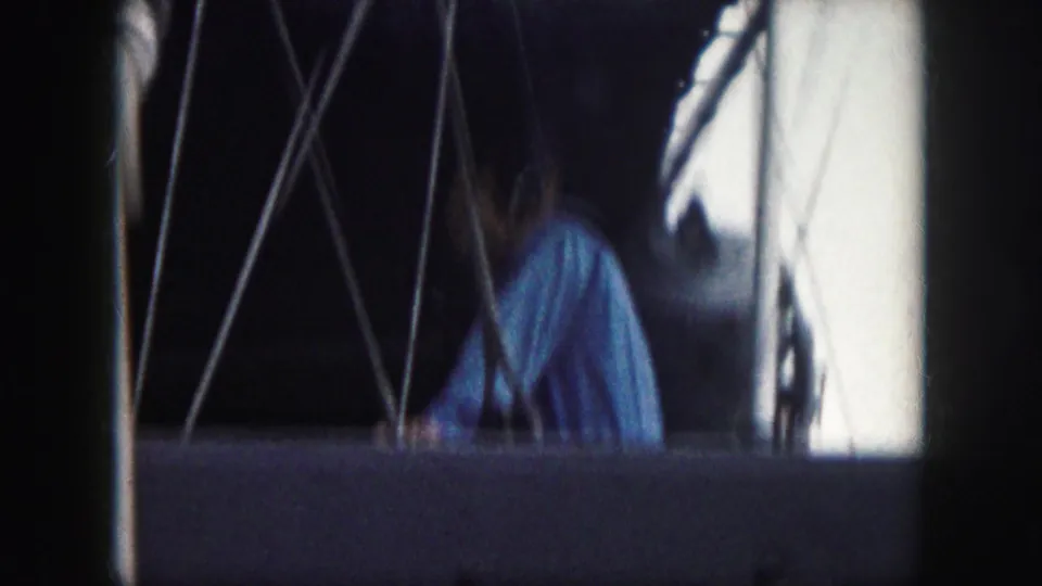 Adult man aboard the boat turns away or looks downward, with rigging and white boat structure visible in this 1959 home-movie frame.