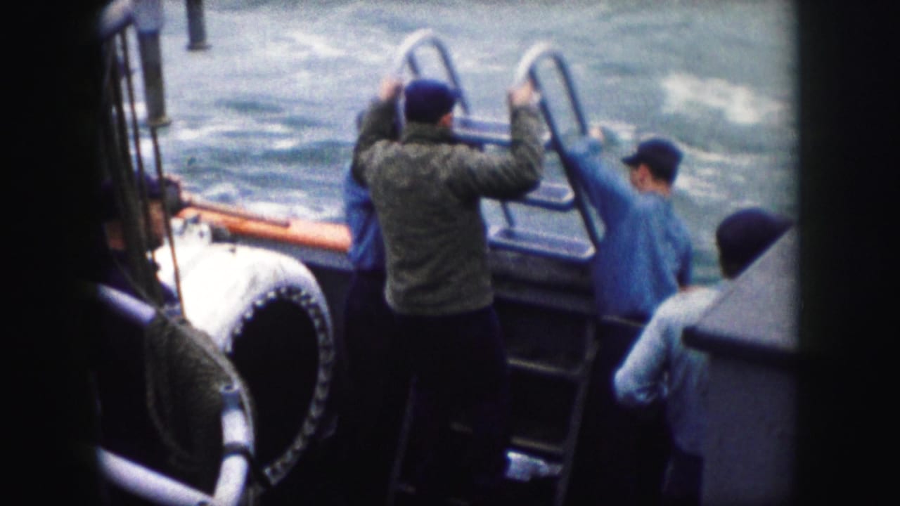 Four adult men on a boat in 1959 home-movie footage handle a metal ladder near the side rail as water moves beside them.