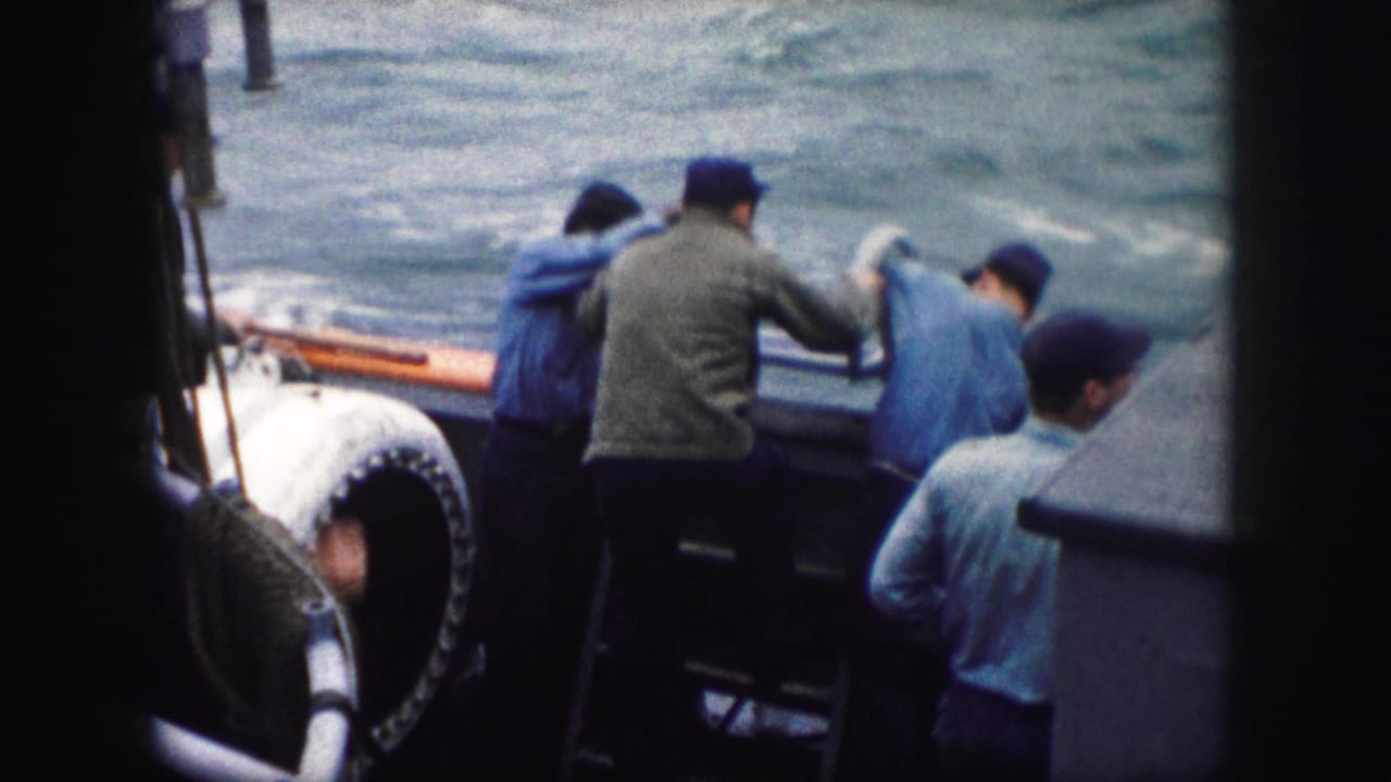 Adult men in caps and jackets appear to steady or position a metal ladder along a boat side, with water visible beyond.