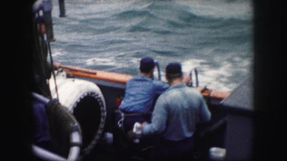 Adult men on the boat shift positions near the side rail after working with the ladder, with choppy water filling the background.