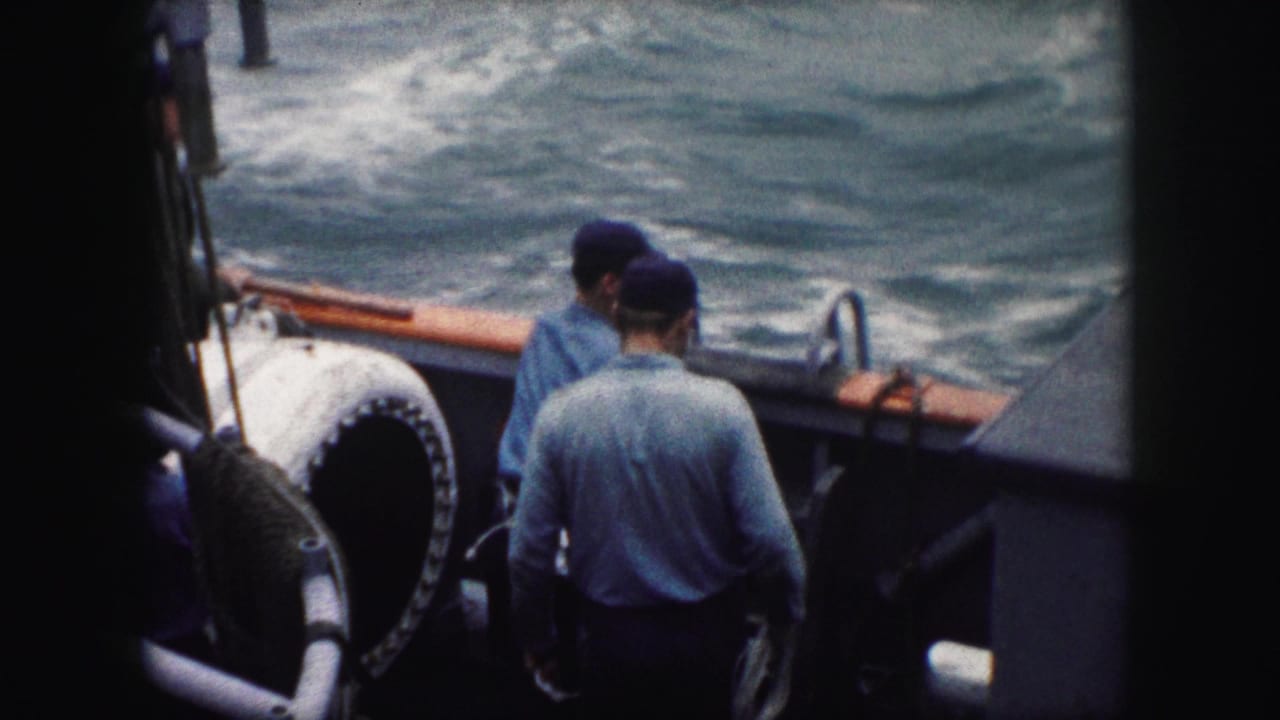 Cataloged 1959 8mm footage shows men on a vessel deck near open water and deck equipment.