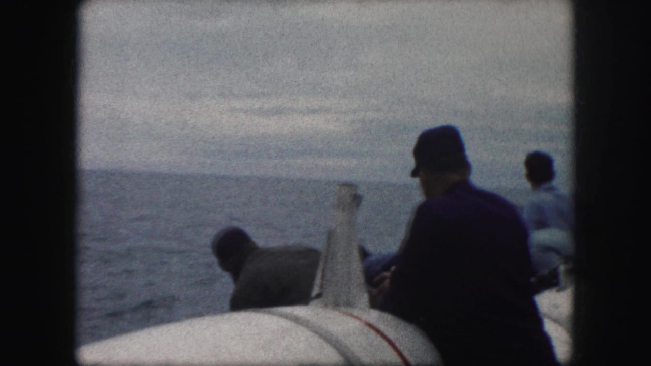 Men aboard the cataloged 1959 vessel appear near large white lifesaving equipment under an overcast sky.
