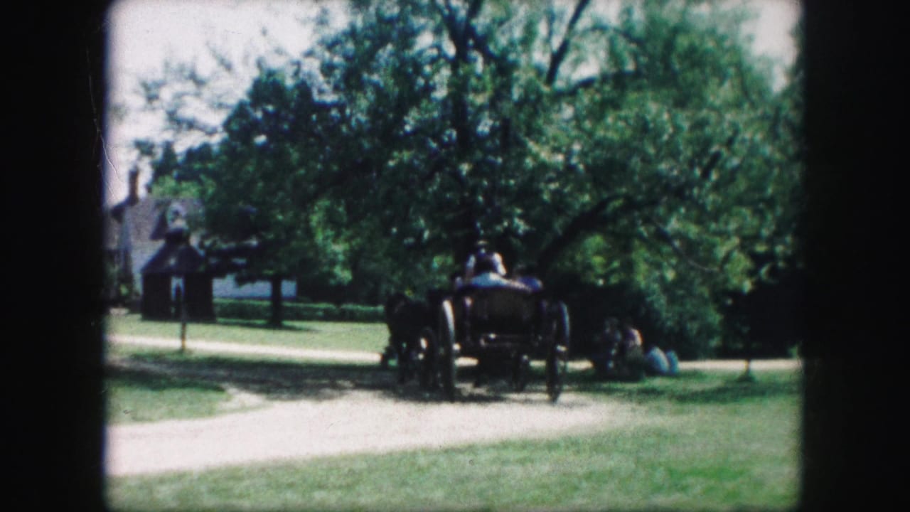 1959 Kansas City home-movie frame showing a horse-drawn wagon moving along a dirt path in a green park-like setting.