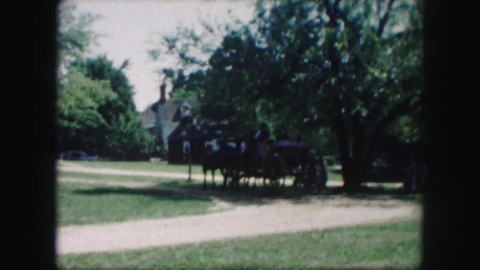 A soft 8mm frame shows the horse-drawn wagon near a curving path, with trees and a building behind it in Kansas City.