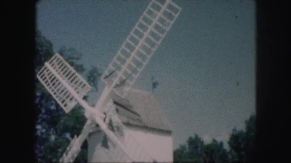 1959 Kansas City frame with the white windmill partly cropped as long lattice blades extend over trees and open sky.