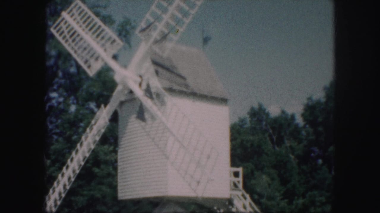 1959 Kansas City 8mm frame showing a white wooden windmill with lattice blades against leafy trees.