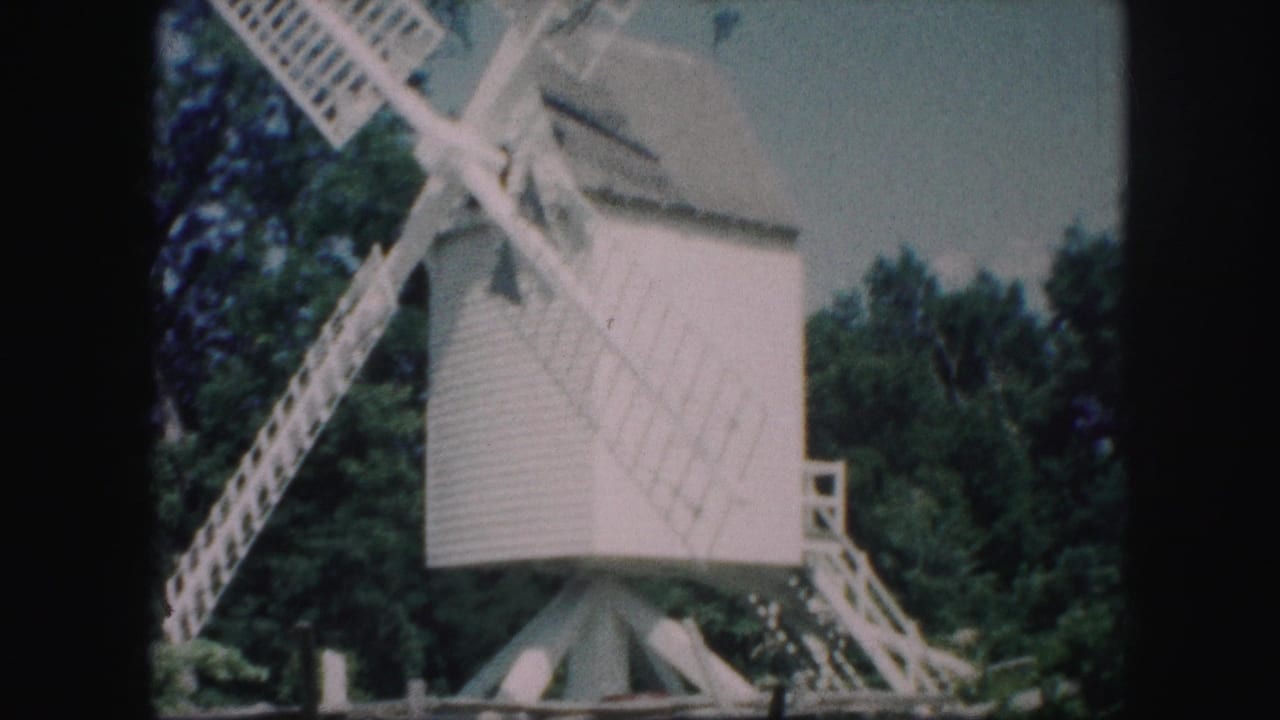 White windmill structure with crossed lattice blades and stairs at right.