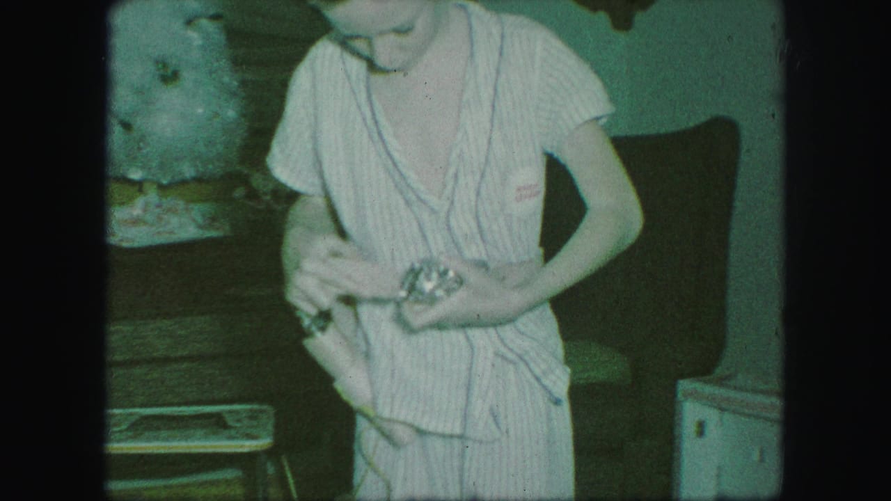 Child in striped pajamas stands indoors holding a cowboy belt near a couch.