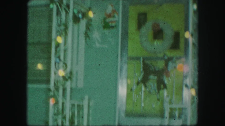 A private porch in the Kansas City home-movie footage shows Christmas lights, a wreath, doorway trim, and a Santa decoration.