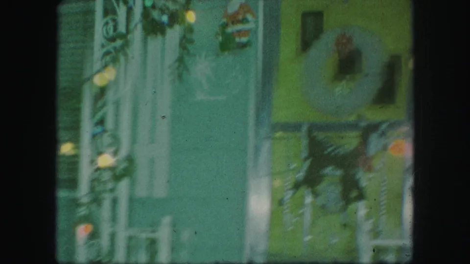 The porch remains framed with holiday lights, a wreath, and a Santa decoration, showing private-property Christmas decor in the 1959 clip.