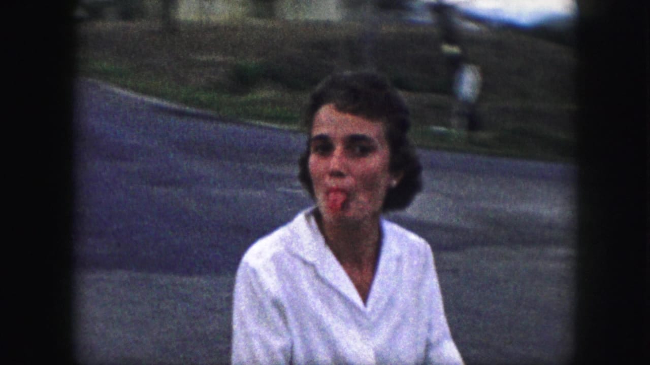 Young woman in a white blouse faces the camera beside a suburban street.