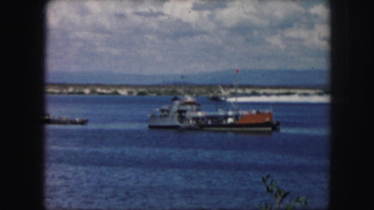 Boat traffic on calm water with a distant shoreline and cloudy sky.