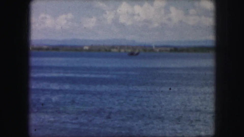 1959 8mm frame supported by metadata showing a small aircraft or seaplane traveling low over a lake near Kansas City, Missouri.