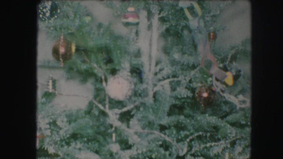 1959 Kansas City 8mm still showing a dense section of decorated Christmas tree with ornaments, chain links, lights, and flocking.