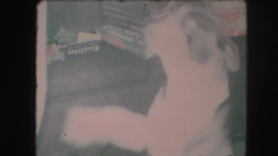 Motion-blurred frame of the small dog jumping indoors near wrapped presents and furniture in a 1959 Kansas City home movie.