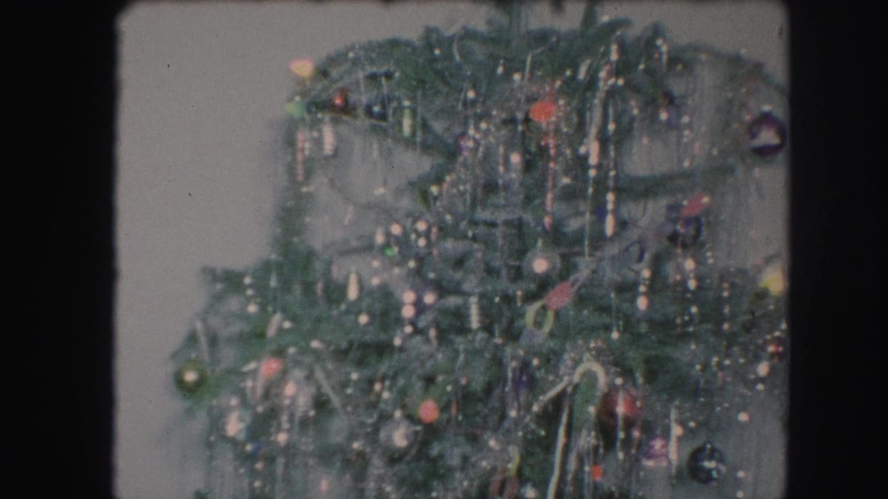 Close view of a decorated green Christmas tree with tinsel and ornaments.