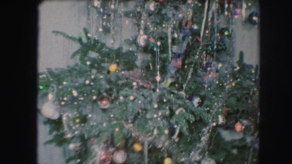 1959 Kansas City 8mm frame showing lower branches of a decorated Christmas tree with tinsel, round ornaments, and hanging trim.