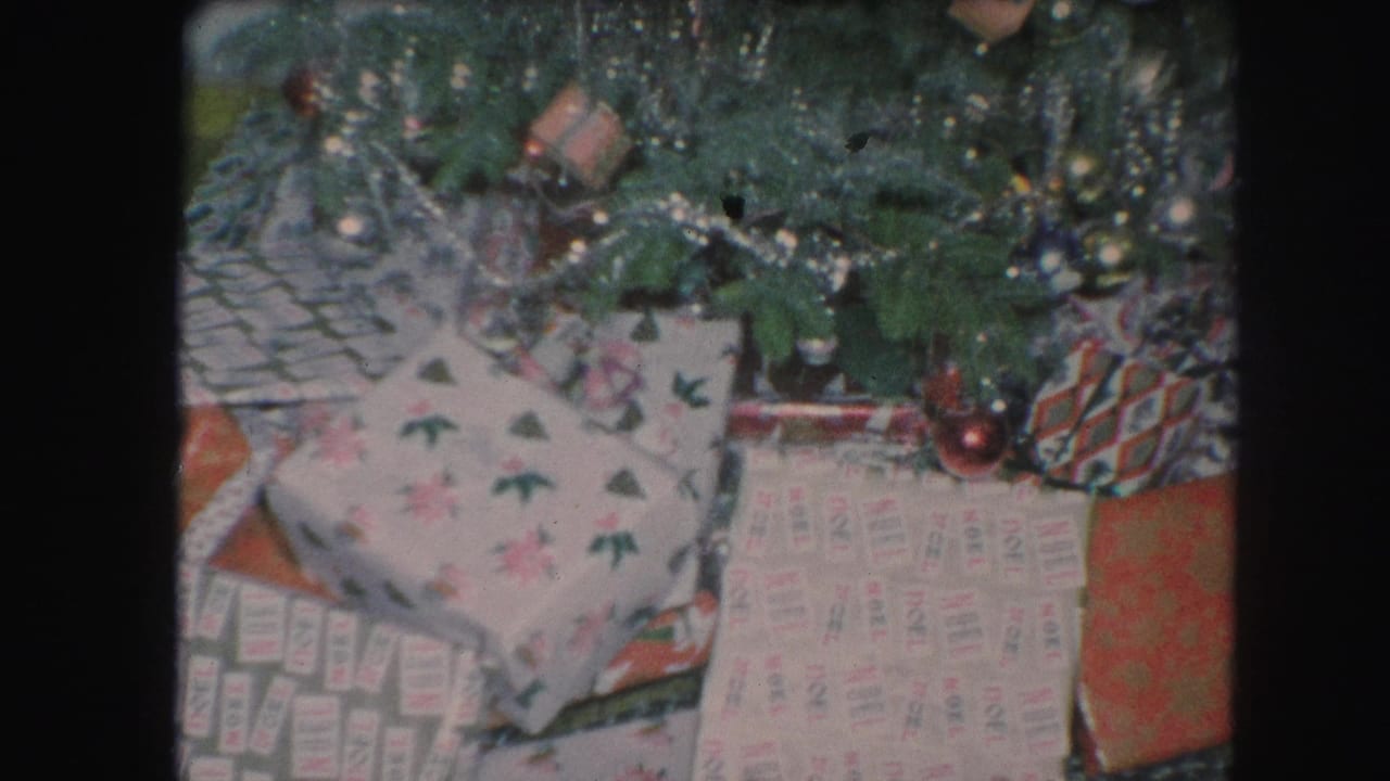Lower Christmas tree branches above wrapped gifts with patterned holiday paper.