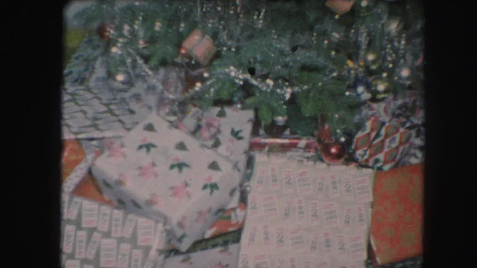 Kansas City 1959 holiday frame focused on lower tree branches, ornaments, tinsel, and wrapped presents on the floor.