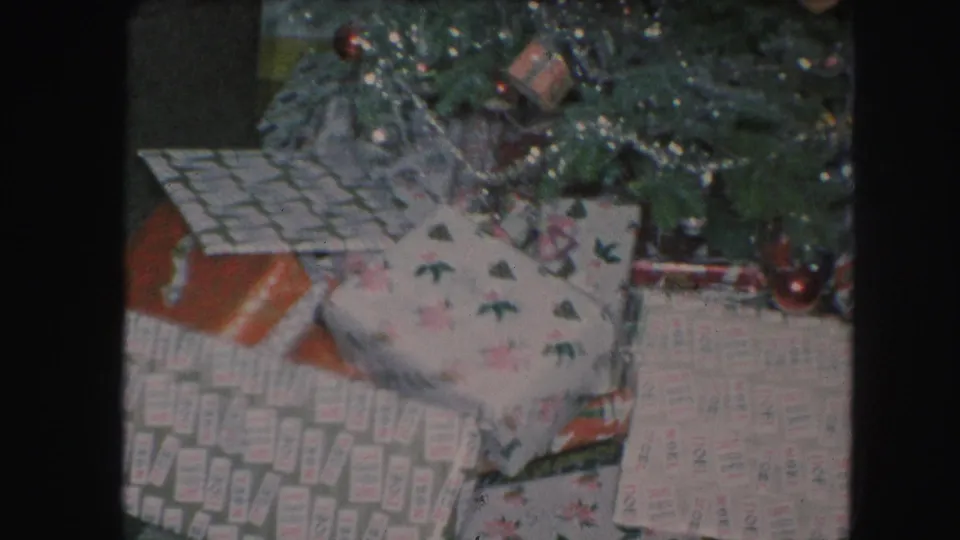 Kansas City 1959 Christmas frame showing gift boxes under a decorated tree with tinsel, ornaments, and muted 8mm color.