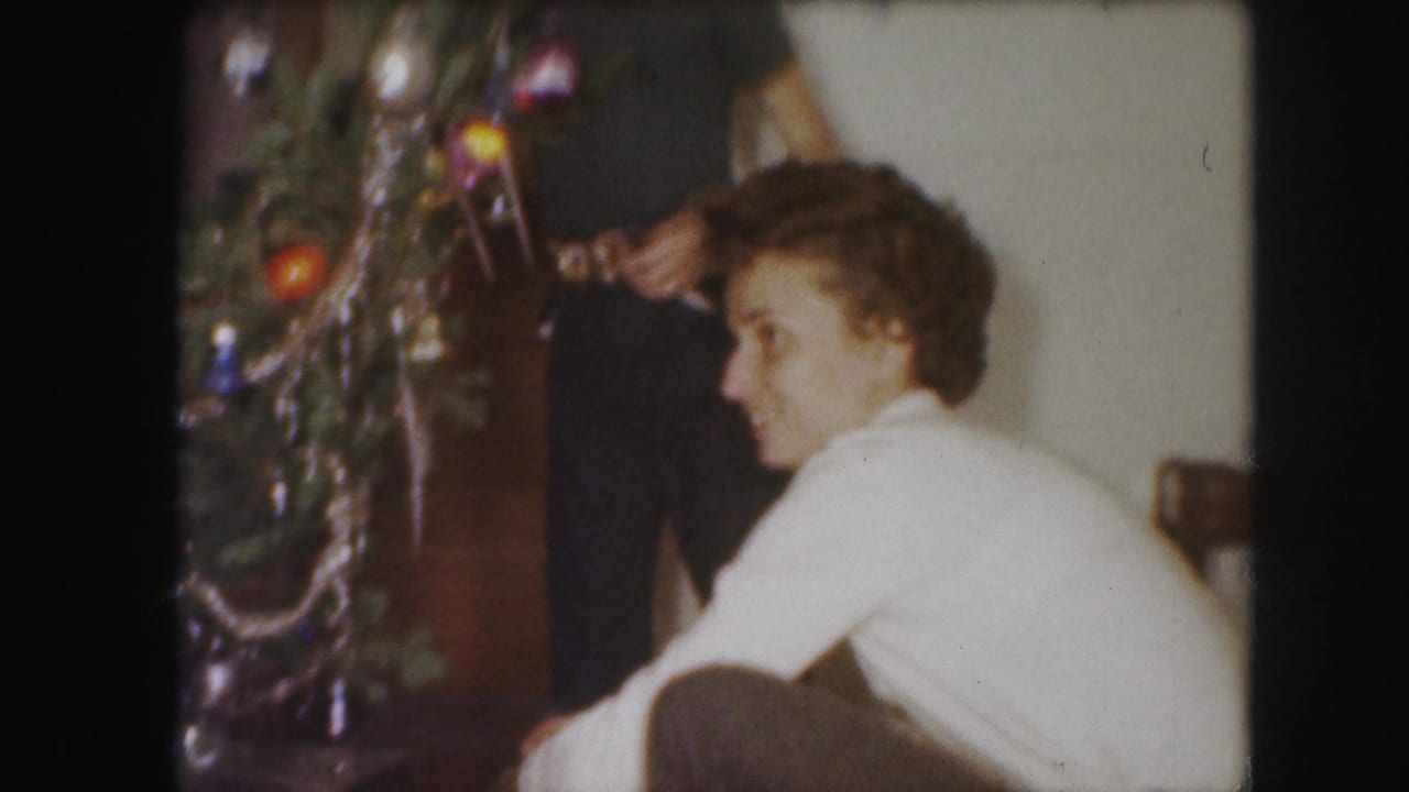 1959 Kansas City home-movie frame with a woman seated near a tinsel-covered Christmas tree in a living room.