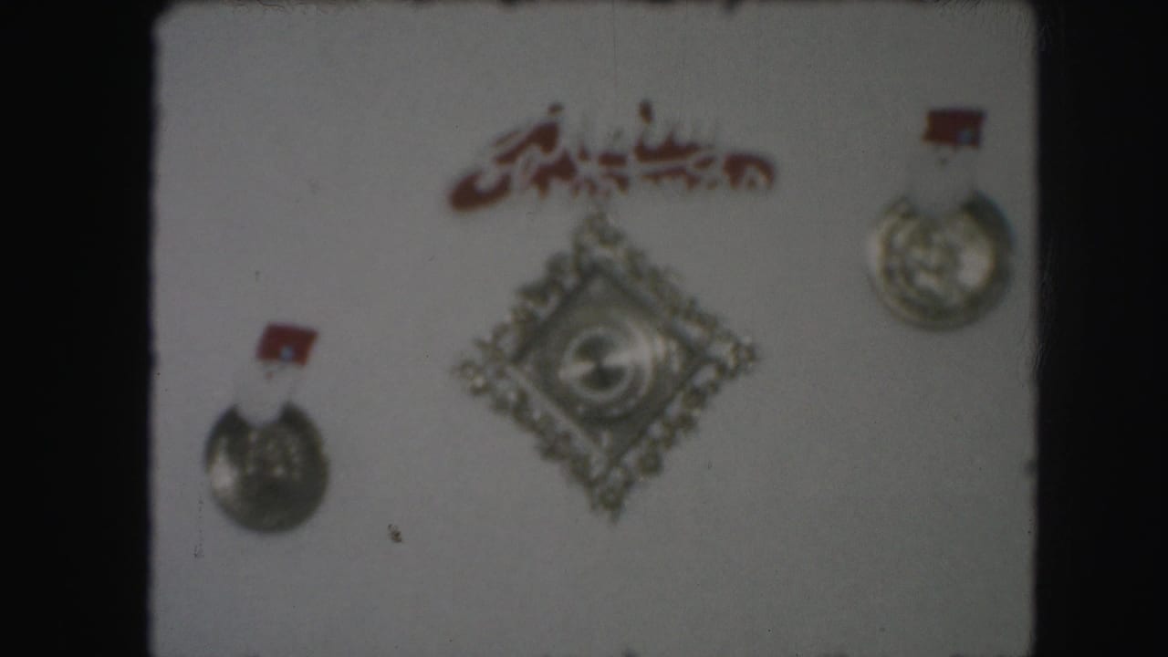 Wall display with silver medals, red script, and a diamond-shaped emblem.