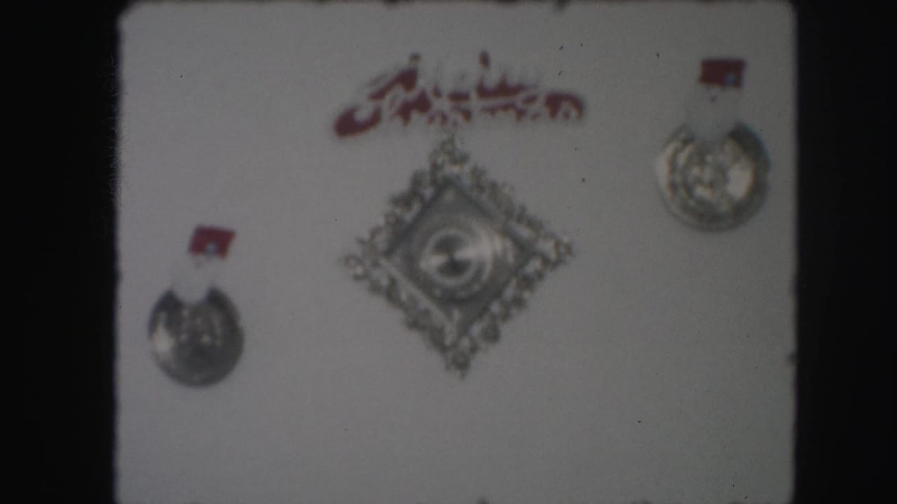 1959 Kansas City home-movie frame showing wall-mounted decorative medallions and an ornament before the ship display appears.