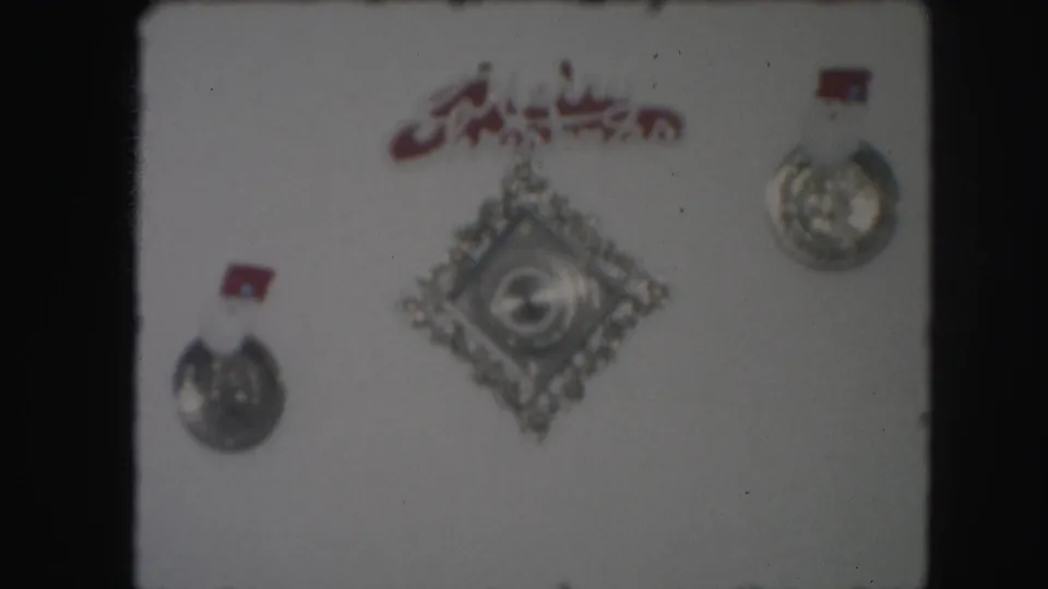 1959 Kansas City home-movie frame showing wall-mounted decorative medallions and an ornament before the ship display appears.
